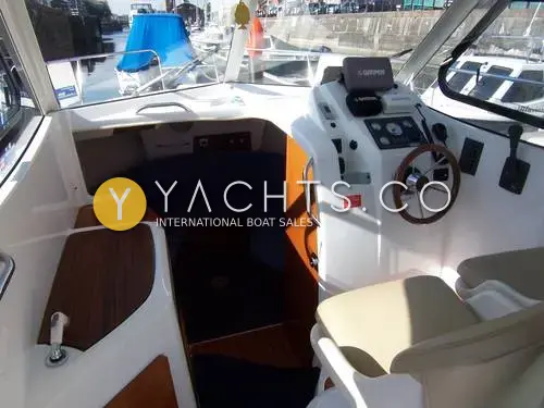 Beneteau Antares 7: wheelhouse interior with starboard helm, cream pilot seats, galley top and blue forward saloon