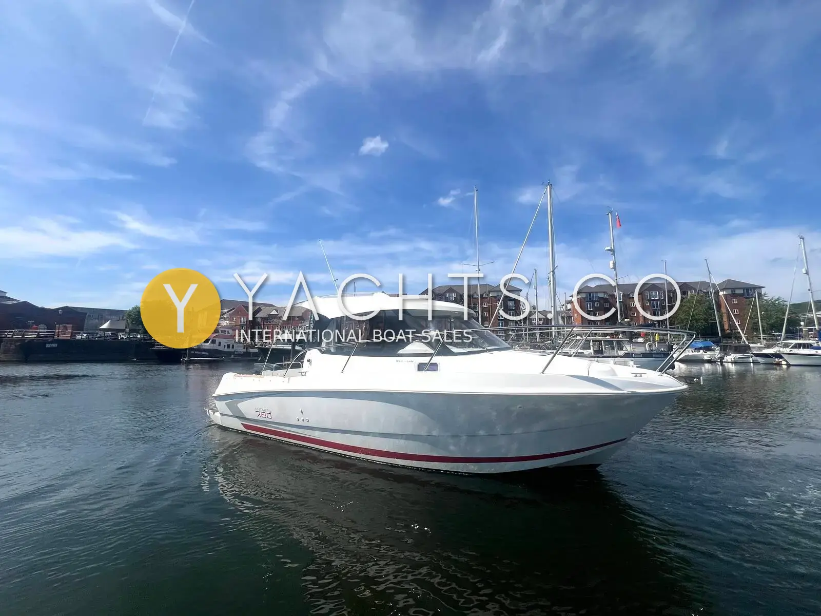 Beneteau Antares 7.80: white hull seen from the starboard bow, moored in a marina under blue sky