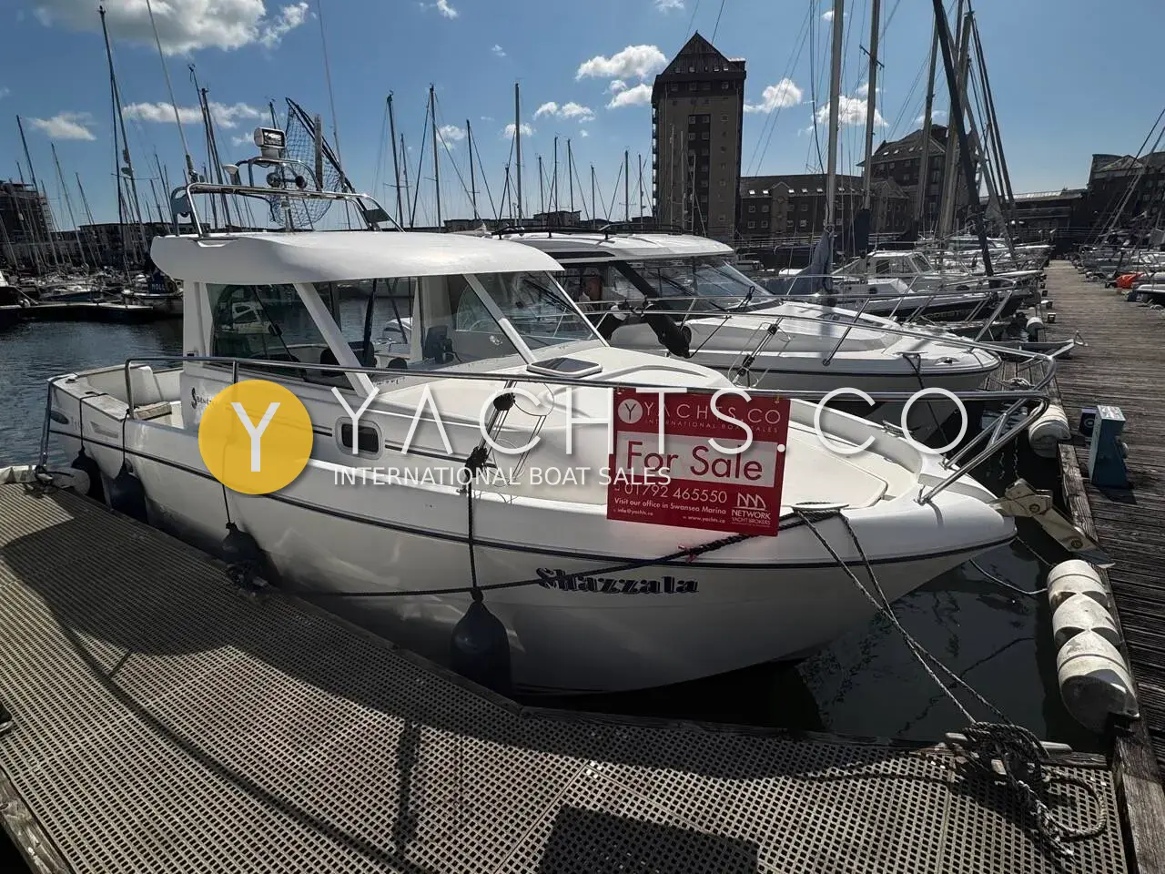 Beneteau Antares 710: white hull with wheelhouse berthed in a marina, sale sign on the cabin side