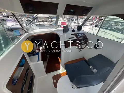 Beneteau Antares 710: wheelhouse interior with starboard helm, grey seats and steps down to the cabin