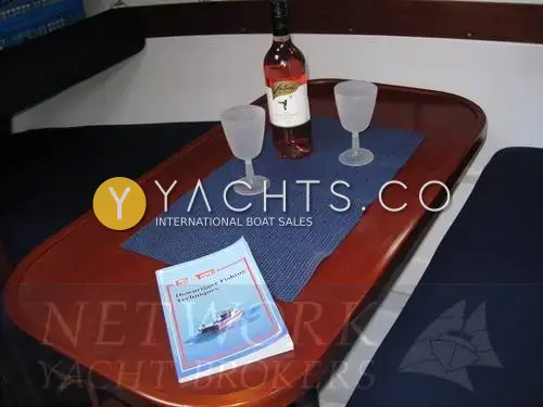Beneteau Antares 710: saloon table in varnished wood with navy upholstered seating either side