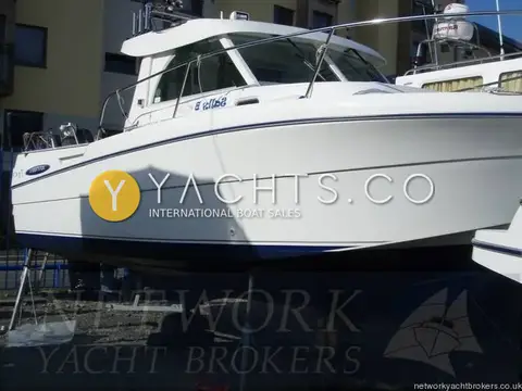 Beneteau Antares 710: starboard side of white hull with blue stripe ashore beside apartment buildings