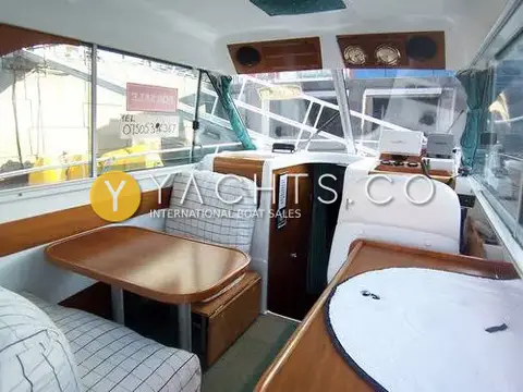 Beneteau Antares 760: wheelhouse saloon with checked-cushion dinette to port and helm seat to starboard