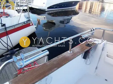 Beneteau Antares 760: stainless cockpit rail with rod holders above teak coaming, marina berth alongside