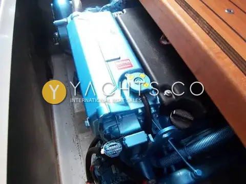 Beneteau Antares 8: engine bay showing the blue diesel engine beneath a lifted wooden floor hatch