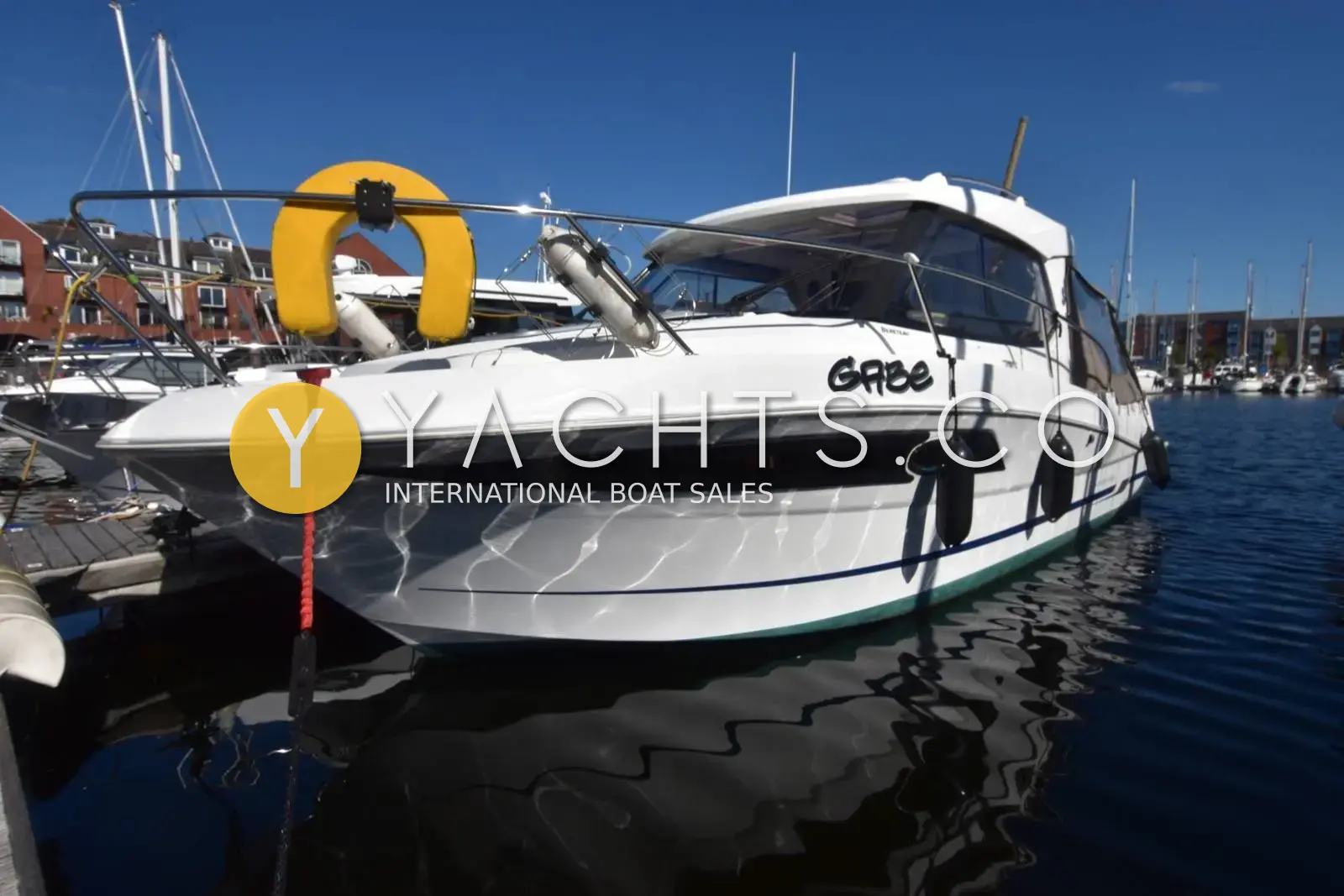 Beneteau Antares 8.80: port bow view of the white hull with name Gabe, moored in a sunny marina
