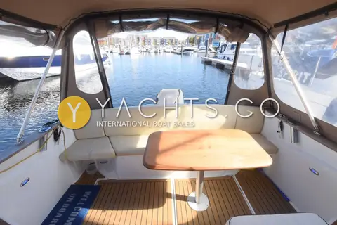 Beneteau Antares 8.80: cockpit under full canvas cover with U-shaped seating, table and teak-effect decking