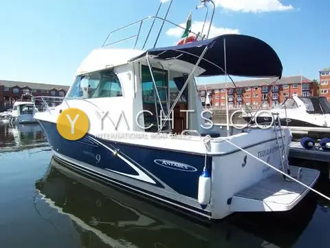 Beneteau Antares 9: starboard quarter view of navy-hulled motor boat with cockpit canopy, moored in marina