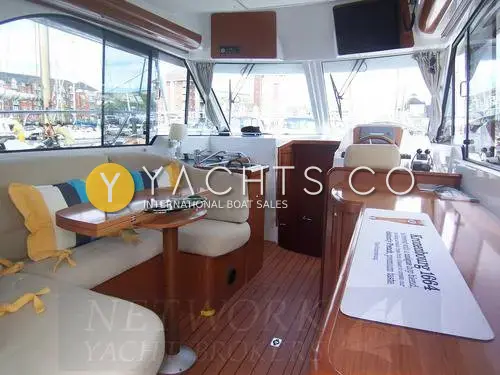 Beneteau Antares 9.80: saloon looking forward past the U-shaped dinette and cherry-wood table to the lower helm