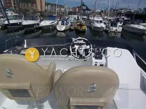 Beneteau Antares 9.80: flybridge helm with twin cream padded seats overlooking a marina of moored motor boats