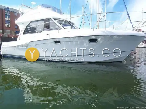 Beneteau Antares 9.80: white hull and flybridge seen from the starboard bow, moored in a marina