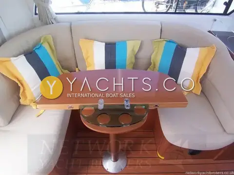 Beneteau Antares 9.80: u-shaped dinette with cream upholstery, striped cushions and folding wooden table