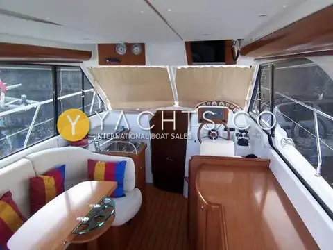 Beneteau Antares 9.80 Anniversary Edition: saloon looking forward to the galley and lower helm, with teak-effect sole and striped cushions