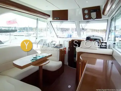 Beneteau Antares 980: saloon looking forward past cream dinette and folding table to the helm and windscreen