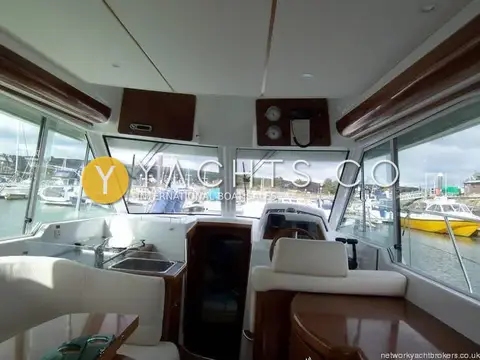 Beneteau Antares 980: wheelhouse view forward over galley sink and helm station towards marina through large windows
