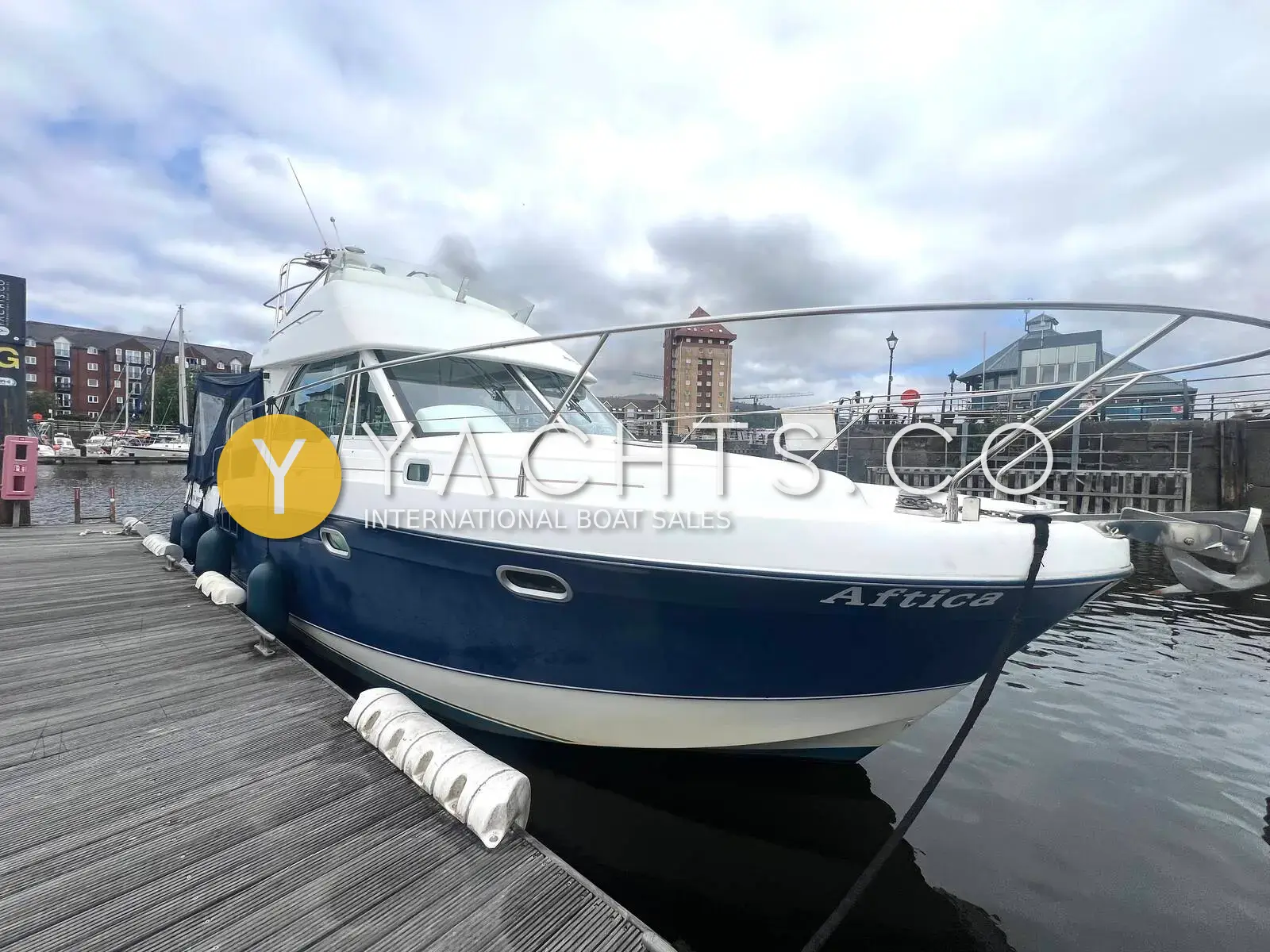 Beneteau Antares 980: blue and white hull with flybridge and radar arch, moored on a pontoon in a city marina