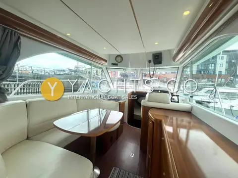 Beneteau Antares 980: saloon with cream leather C-shaped seating, gloss wood table and helm station ahead