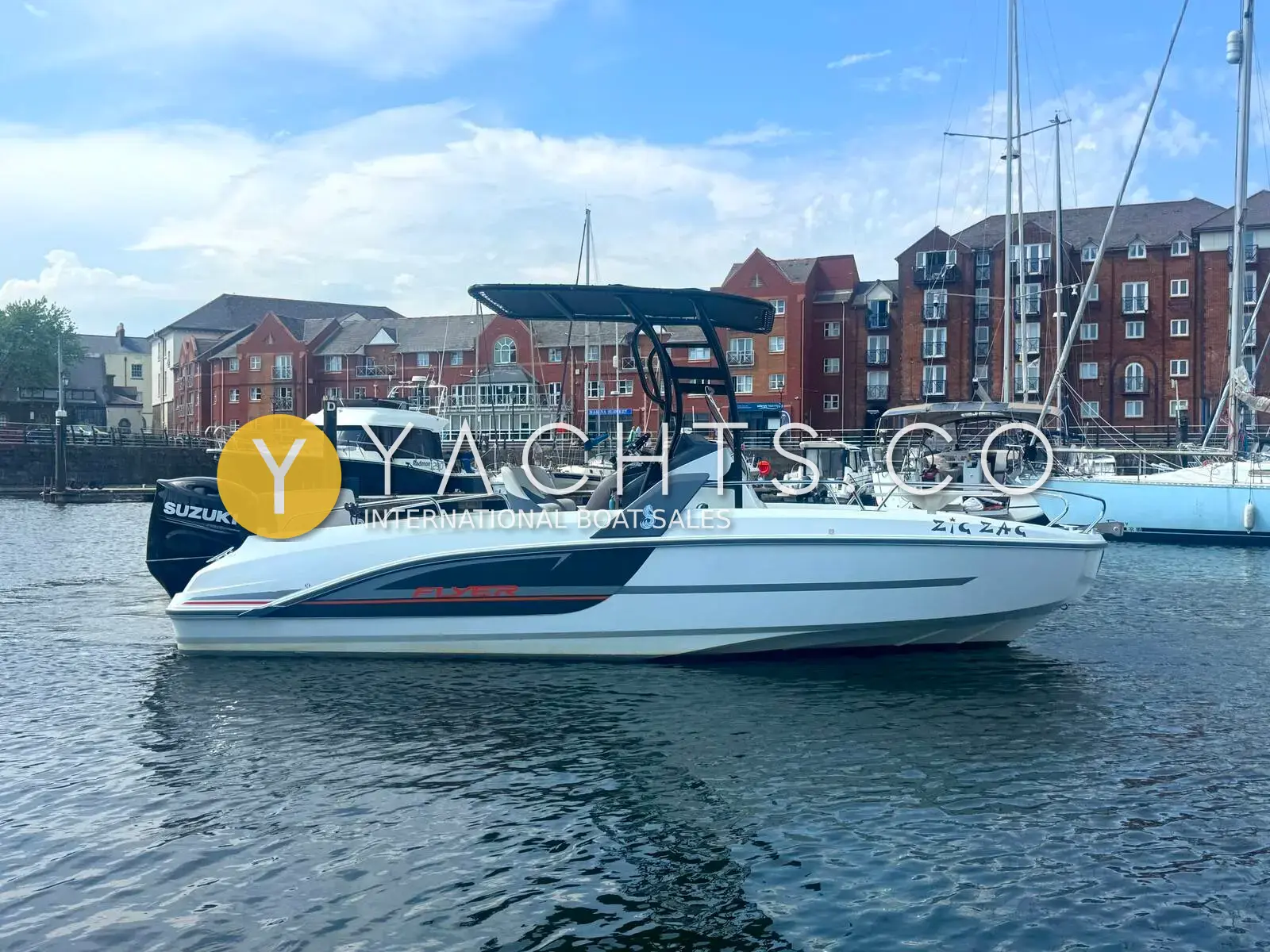 Beneteau Flyer 6.6 SpaceDeck: starboard side view of white hull with black T-Top, moored in a marina beside brick buildings