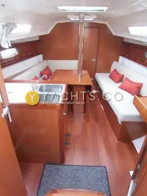 Beneteau Oceanis 31: saloon looking forward, cherry-toned joinery, cream upholstery, red cushions and twin galley sinks