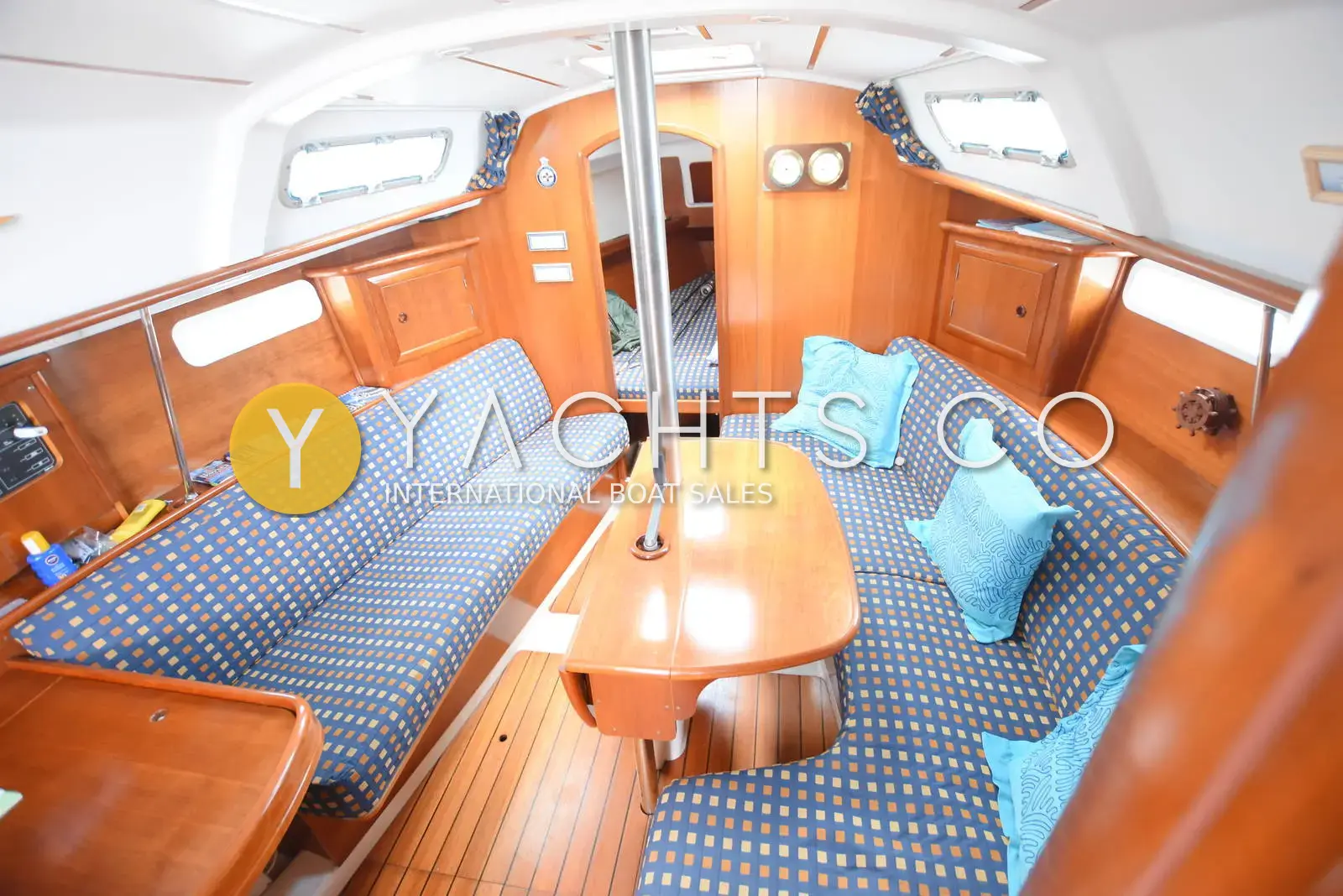 Beneteau Oceanis 331 Clipper: saloon with blue patterned upholstery, light blue cushions and folding table, looking forward