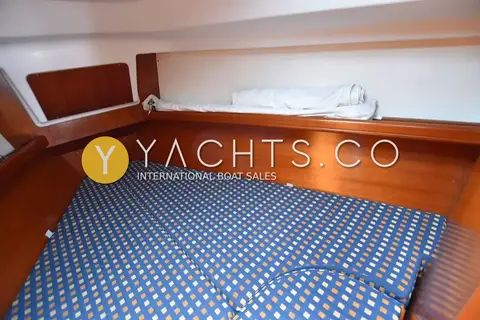 Beneteau Oceanis 331 Clipper: double berth with blue patterned cushions, folded bedding and wooden bulkhead