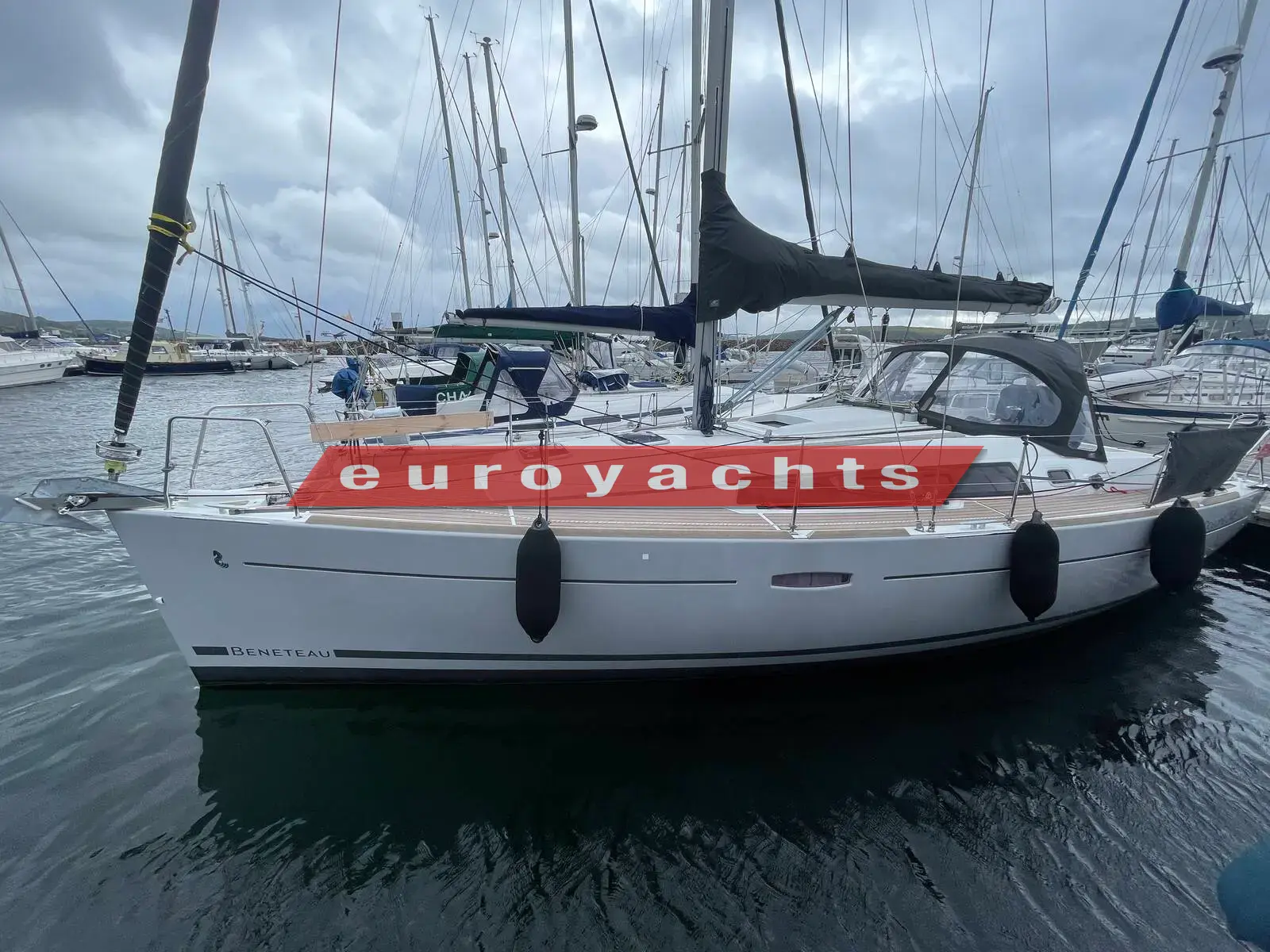Beneteau Oceanis 34: grey-hulled yacht afloat in marina, starboard side with sprayhood and furled sails