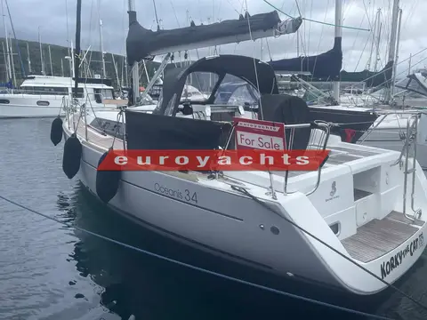 Beneteau Oceanis 34: stern quarter view showing dark sprayhood, fenders and sugar scoop at a pontoon
