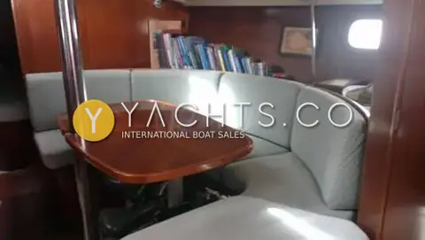 Beneteau Oceanis 351: saloon with curved pale blue upholstered seating around a varnished wooden table
