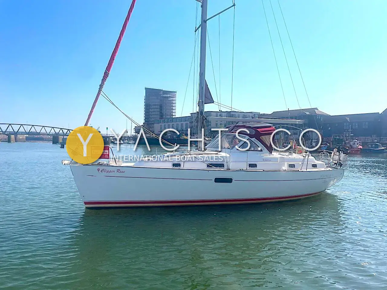 Beneteau Oceanis 36CC: starboard side of the white sloop afloat in a marina, burgundy sprayhood and bridge behind