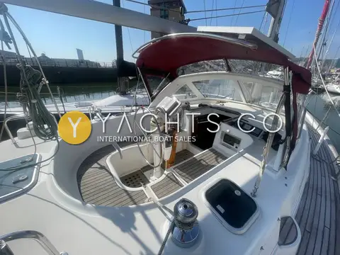 Beneteau Oceanis 36CC: centre cockpit under burgundy bimini frame with teak-laid seats and wheel binnacle