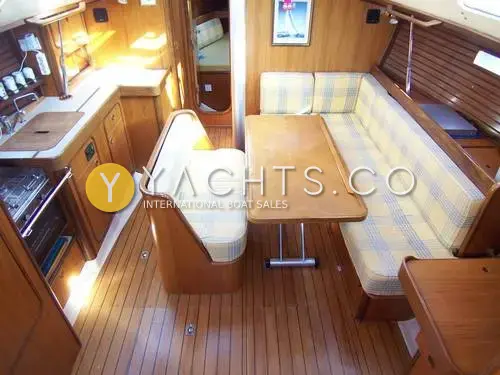 Beneteau Oceanis 390: saloon with checked upholstered seating, folding table, teak-and-holly sole and galley to port