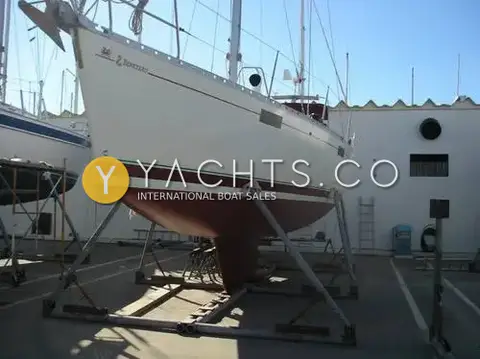 Beneteau Oceanis 390: hull ashore on cradle in a boatyard, showing burgundy antifouling and wing keel
