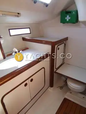 Beneteau Oceanis 390: heads compartment with white moulded vanity, wood trim, toilet and wall-mounted first aid kit