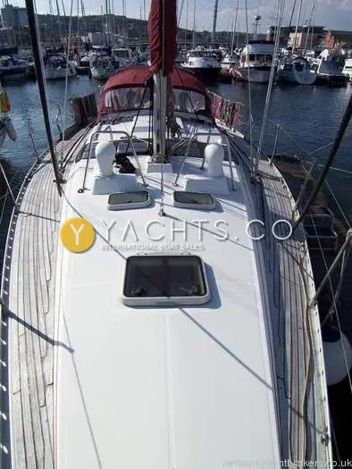 Beneteau Oceanis 390: foredeck looking aft to the burgundy spray hood, with deck hatch and teak side decks