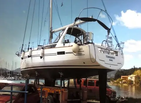 Beneteau Oceanis 41 Express: hull ashore on stands showing transom and stern, hills and water behind