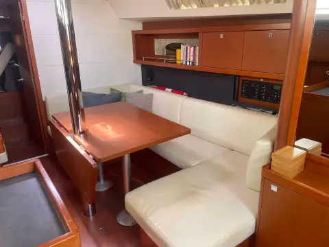 Beneteau Oceanis 41 Express: saloon with cream L-shaped seating, wooden table and bookshelf above