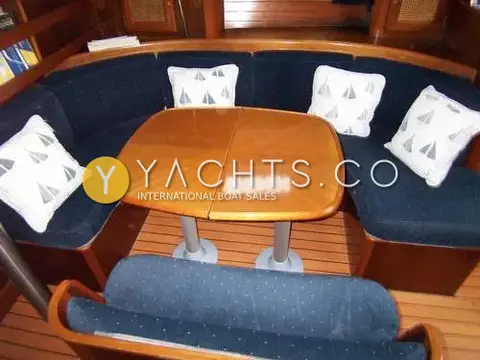 Beneteau Oceanis 411 Clipper: saloon with blue fabric curved seating, folding wooden table and sailboat-print cushions