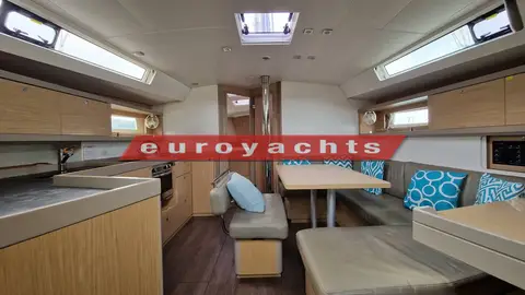 Beneteau Oceanis 45: saloon looking forward, galley to port and dining table with blue cushions to starboard