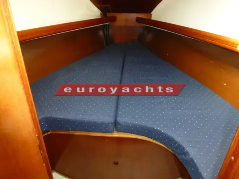 Beneteau Oceanis Clipper 323: forward cabin V double berth with blue upholstered cushions and wooden shelving