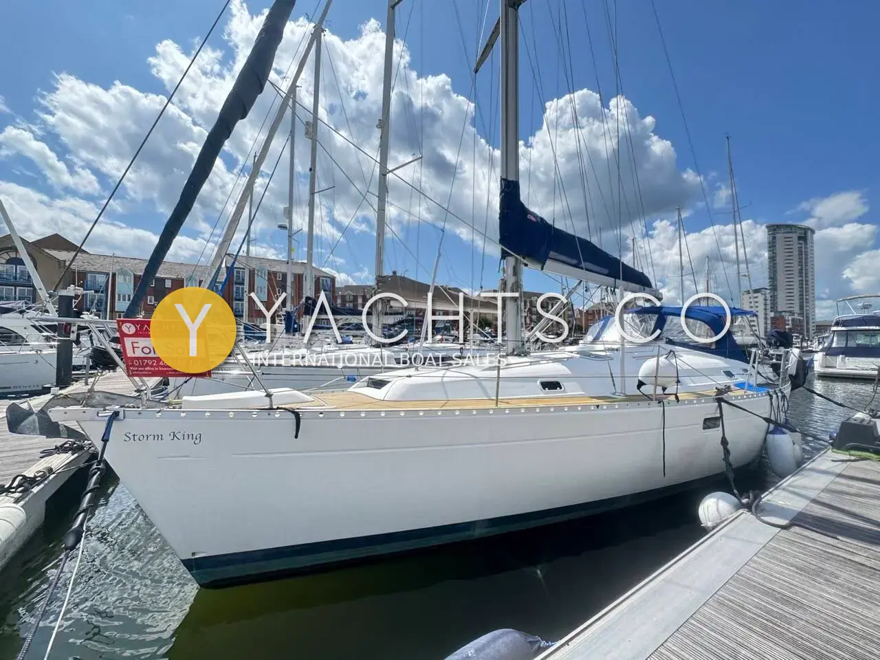 Beneteau Oceanis Clipper 381: white hull on a marina pontoon with blue sprayhood and furled mainsail cover