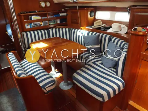 Beneteau Oceanis Clipper 411: saloon dinette with striped cushions, folding wooden table and bookshelf