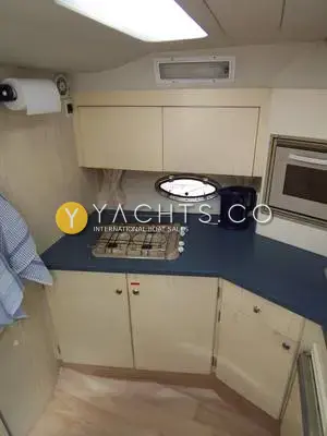 Birchwood Challenger 320: galley with gas hob, blue worktop, pale wood cupboards, built-in oven and porthole