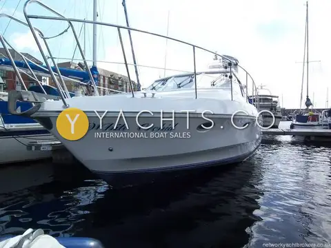 Birchwood Challenger 320: bow quarter view of the white hull with guardrails, moored on a marina pontoon