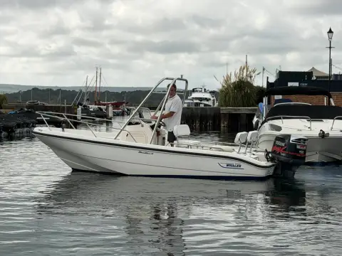 Boston Whaler Dauntless 18: port side view underway slowly in the marina, low profile hull and centre console