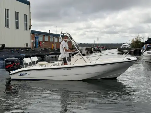 Boston Whaler Dauntless 18: starboard side view afloat in a marina, skipper standing at the centre console