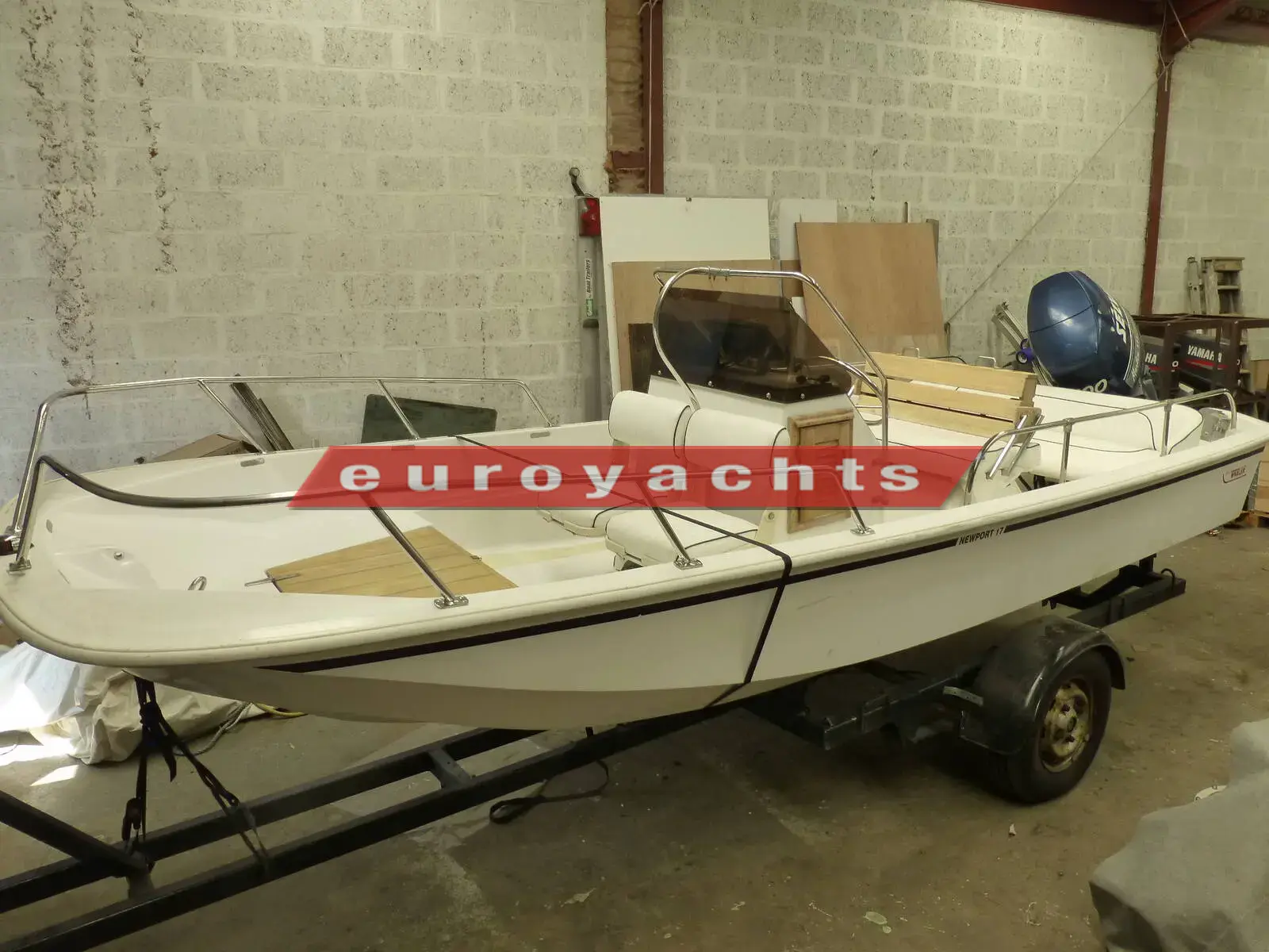 Boston Whaler Newport 17: white centre console boat on a trailer in a workshop, outboard at the stern