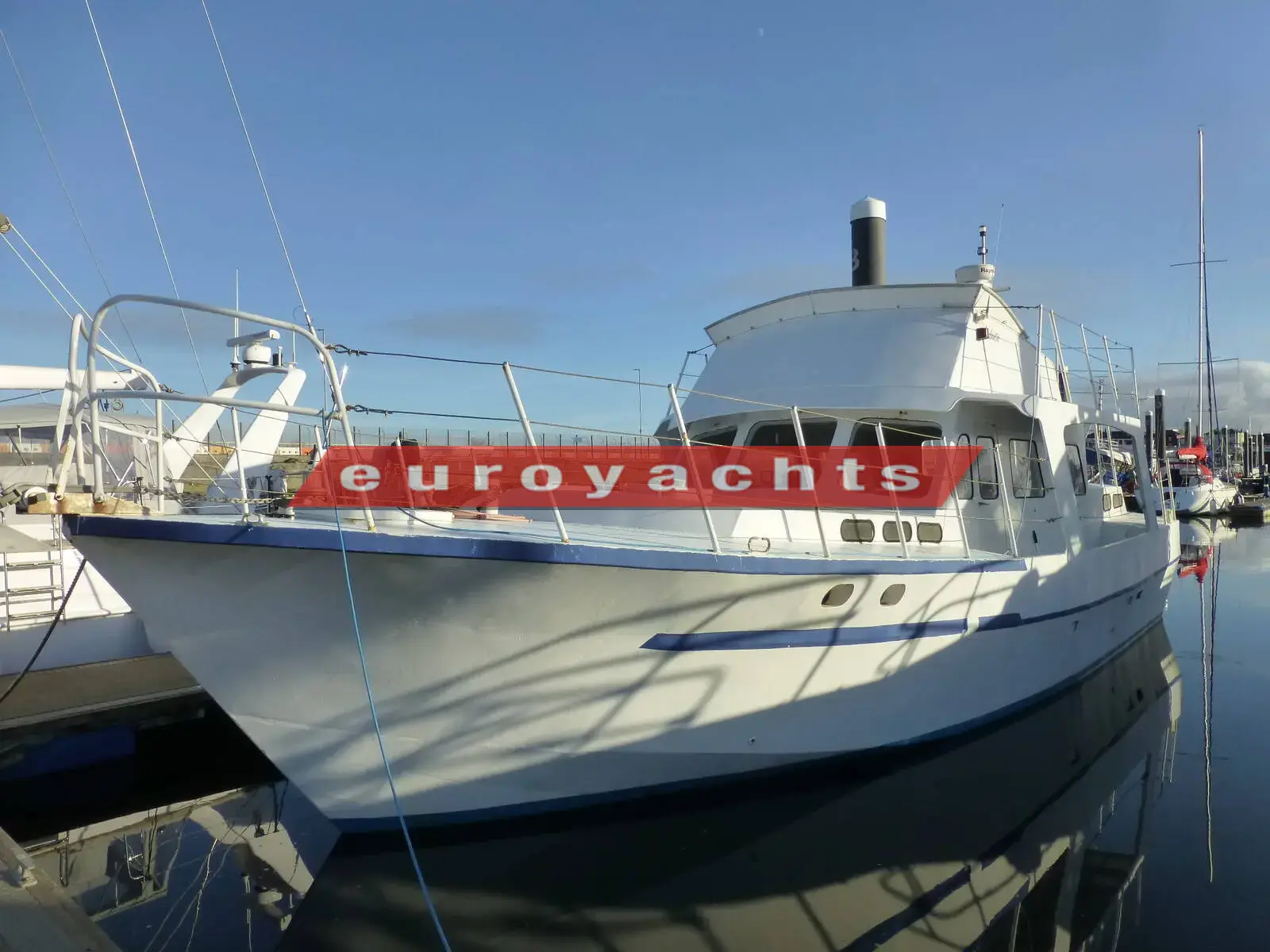 Bruce Roberts Waverunner 45: starboard bow view of the white steel hull moored in a marina under clear blue sky