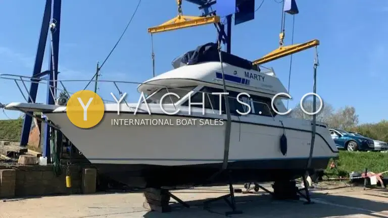 Carver 26 Command Bridge: white flybridge hull ashore on blocks in a boatyard, with a travel hoist alongside