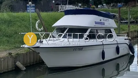 Carver 26 Command Bridge: bow and starboard side afloat on a river mooring, blue canopy over the flybridge