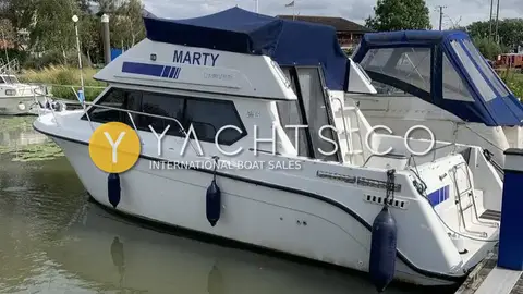 Carver 26 Command Bridge: port side afloat with fenders out, name on the flybridge and covered aft cockpit